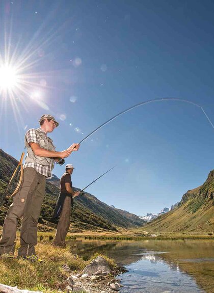 Zwei Angler, die an einem kleinen Weiher umgeben von einer Bergkulisse fischen | © Golm Silvretta Lünersee Tourismus GmbH Bregenz, Patrick Saely
