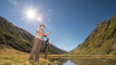Zwei Angler, die an einem kleinen Weiher umgeben von einer Bergkulisse fischen | © Golm Silvretta Lünersee Tourismus GmbH Bregenz, Patrick Saely